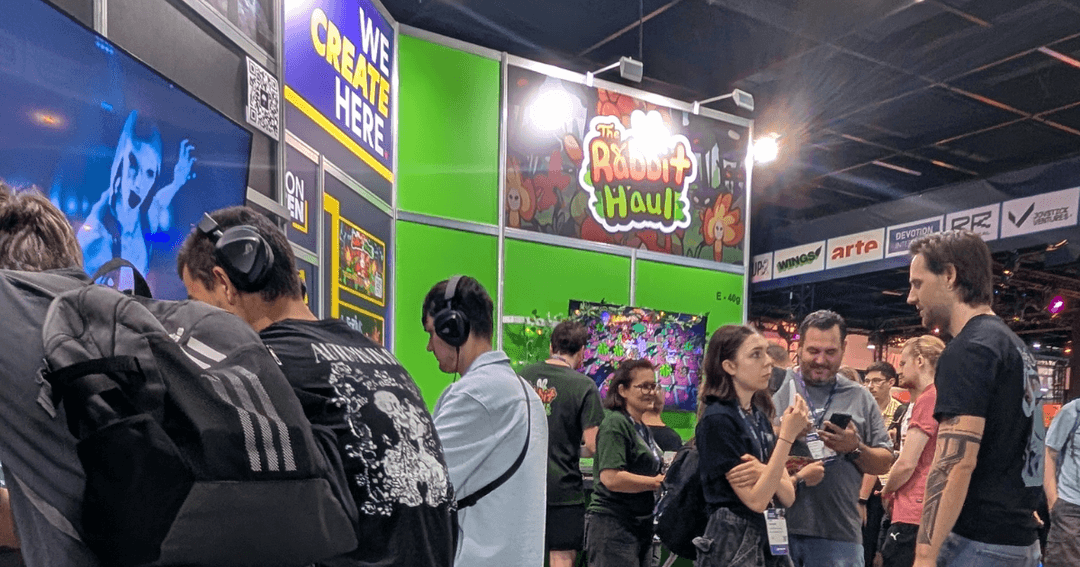 Attendees of gamescom 2026 at the Edmonton Screen booth, demoing games from local Edmonton indie studios who were a part of Edmonton Screen's Summit Push Program. The Rabbit Haul and Lucid Rain Studios' booth is visible, with Edmonton's slogan, "We Create Here", seen.