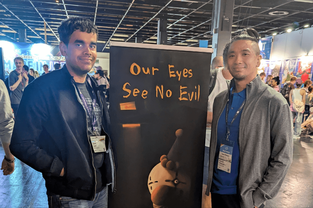 Dave Goel, Co-Founder and Producer of COG Studios, an Edmonton-based indie game studio, smiling next to a banner featuring the most recent game title, Our Eyes See No Evil, and Edmonton Screen's Digital Media & Technology Specialist, Ronnie Villanueva.